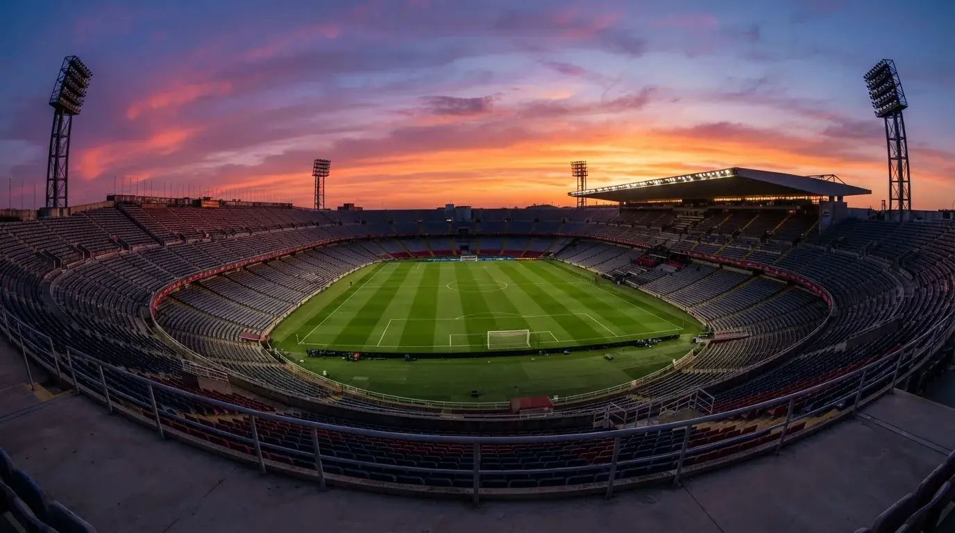 Un estadio de fútbol vacío con torres de iluminación al atardecer